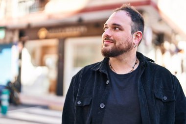 Young hispanic man smiling confident looking to the side at street