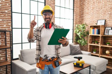 Evde çalışan sakallı genç bir İspanyol bir adam bir fikir veya soruyla gülümsüyor ve mutlu bir yüzle işaret ediyor. 