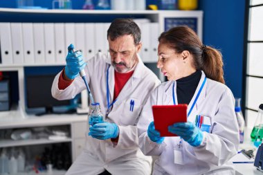 Laboratuvarda çalışan orta yaşlı erkek ve kadın bilim adamları