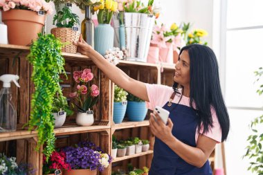 Çiçekçiye akıllı telefon kullanarak gülümseyen İspanyol çiçekçi kadın.