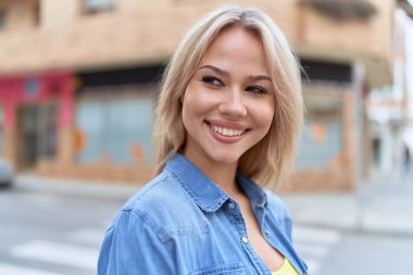 Young blonde woman smiling confident looking to the side at street