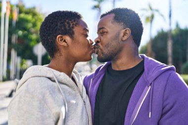 Erkek ve kadın çift parkta spor kıyafeti giyip öpüşüyor.