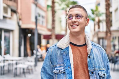 Young hispanic man smiling confident looking to the side at street
