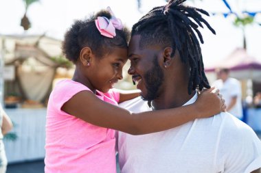 Father and daughter smiling confident hugging each other at street market