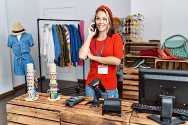 Kafkasyalı genç esnaf gülümseyip, mağazada çalışan akıllı telefondan konuşmaktan mutlu oluyor..