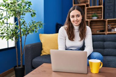 Genç ve güzel İspanyol kadın dizüstü bilgisayar kullanıyor. Evde kahve içiyor.