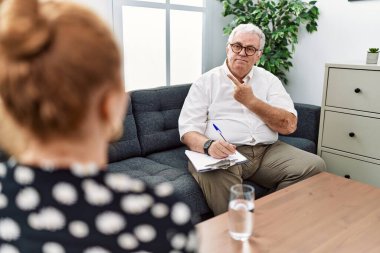 Konsültasyondaki kıdemli psikolog endişeli ve endişeli bir ifadeye işaret ediyor. 