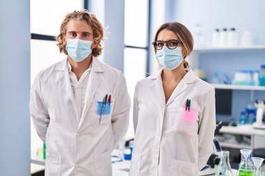 Man and woman wearing scientist uniform and medical mask at laboratory