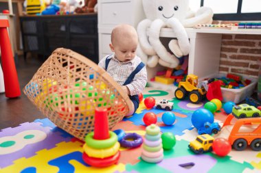 Sevimli beyaz bebek anaokulunda yerde taşaklarıyla oynuyor.