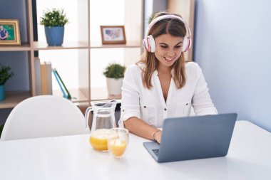 Young woman using laptp drinking orange juice at home