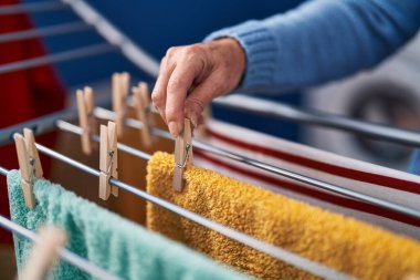 Middle age woman hanging clothes on clothesline at laundry room