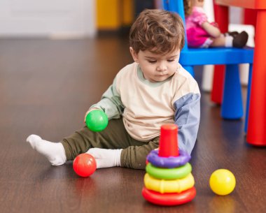 Sevimli İspanyol çocuk anaokulunda yerde oturmuş hayalarıyla oynuyor.