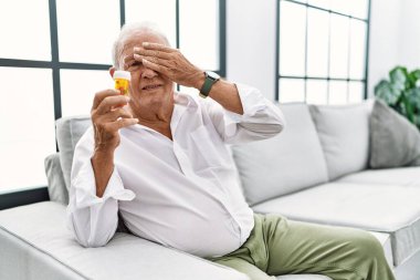 Son sınıf öğrencisi elinde haplarla gülümsüyor ve elleri yüzünde, şaşırtmak için gözlerini kapatıyor. kör kavram. 