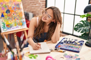 Sanat stüdyosunda kendine güvenen güzel İspanyol bir sanatçı çiziyor.