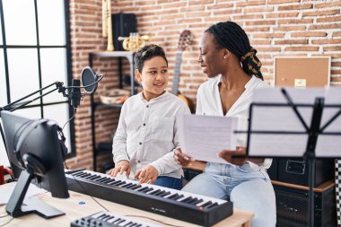 African american mother and son student learning play piano at music studio