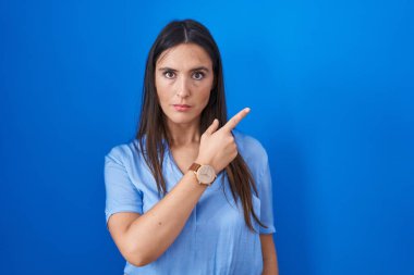 Mavi arka planda duran genç esmer kadın, elini yana uzatarak reklamını yapıyor, ciddi ve sakin bir yüz ifadesi var. 