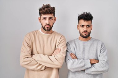 Young homosexual couple standing over white background skeptic and nervous, disapproving expression on face with crossed arms. negative person. 