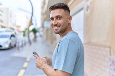 Sokakta akıllı telefon kullanan, kendine güvenen genç bir İspanyol.