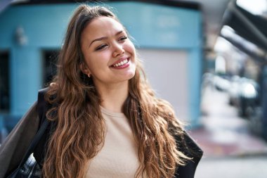 Young beautiful hispanic woman smiling confident looking to the side at street