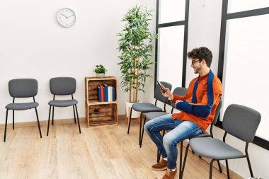 Genç İspanyol adam, klinikteki bekleme odasında sandalyeye otururken akıllı telefon kullanarak yaralandı.