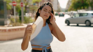 Genç ve güzel İspanyol kadın, sokakta acı çekmek için el fanı kullanıyor.