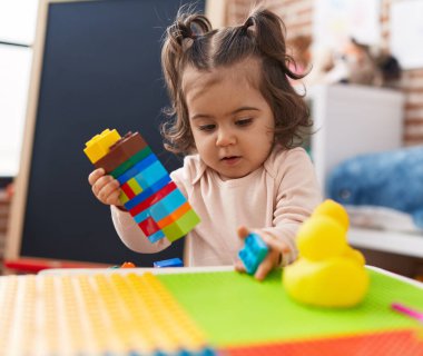 Anaokulunda inşaat bloklarıyla oynayan sevimli İspanyol kız.