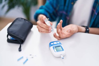 Evdeki masada oturan glikoz ölçen genç İspanyol adam.