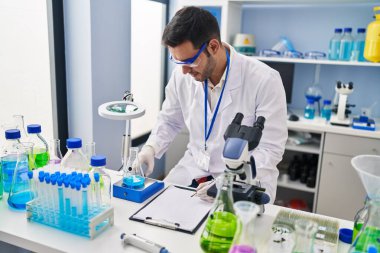 Genç İspanyol bilim adamı laboratuvarda sıvı yazım raporunu ölçüyor.