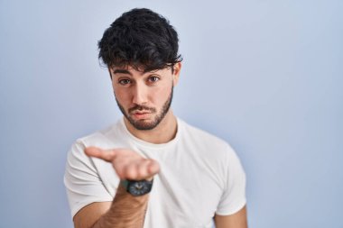 Beyaz arka planda sakallı İspanyol bir adam kameraya bakıp havada bir öpücük savuruyor ve sevimli ve seksi. aşk ifadesi. 