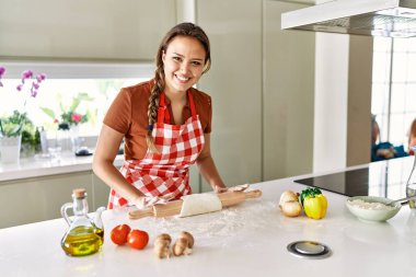 Genç, güzel, İspanyol bir kadın. Mutfakta kendine güvenen hamur pizzası.