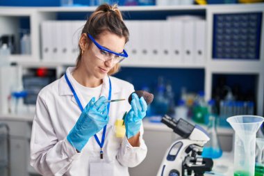 Young woman scientist looking fruit with loupe at laboratory