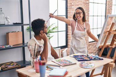 Man and woman artists smiling confident drawing on notebook at art studio