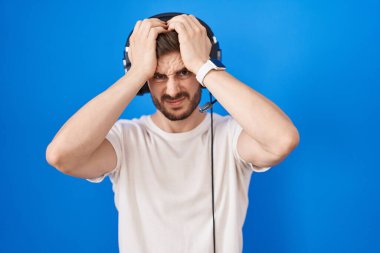 Sakallı, kulaklık takan, baş ağrısı çeken, çaresiz ve stresli bir İspanyol adam. Çünkü acı ve migren. Eller başının üstünde.. 