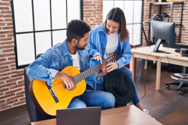 Man and woman musicians having classical guitar lesson at music studio