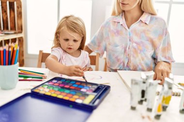 Mother and daughter smiling confident drawing on notebook at art studio