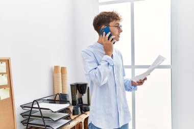 Young caucasian man talking on the smartphone working at office