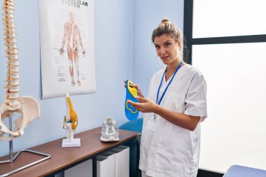 Genç sarışın kadın podiyatrist klinikte tabanı tutuyor.