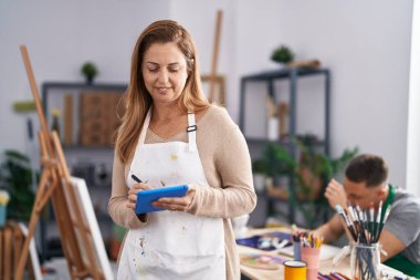 Erkek ve kadın sanatçılar sanat stüdyosunda dokunmatik kağıt kullanarak deftere çizim yapıyorlar.
