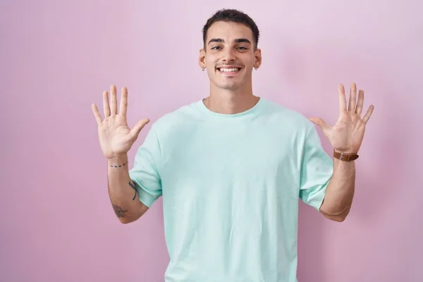 Pohledný Hispánec Stojící Nad Růžovým Pozadím Ukazující Ukazující Prsty Číslo — Stock fotografie