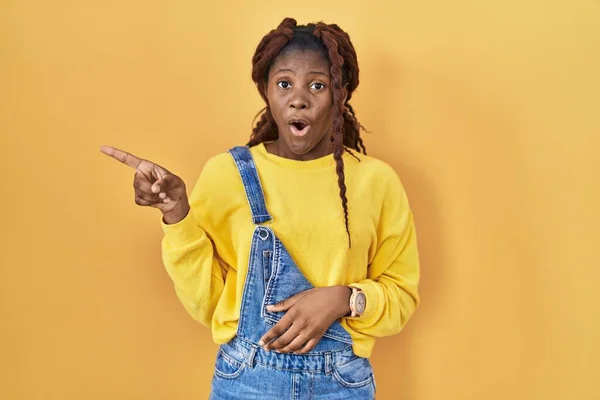 African Woman Standing Yellow Background Surprised Pointing Finger Side Open — Stockfoto