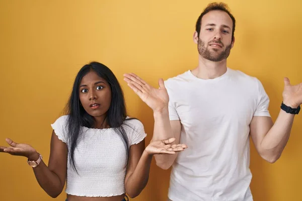 Interracial Couple Standing Yellow Background Clueless Confused Expression Arms Hands — Stock fotografie