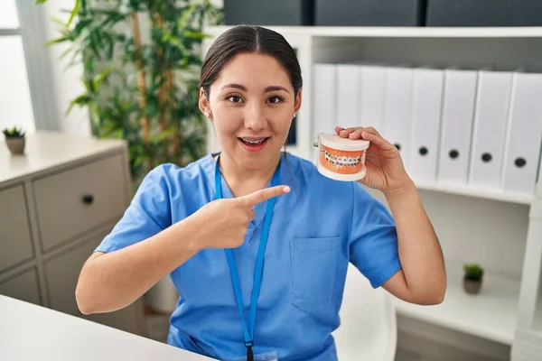 Young Latin Dentist Woman Holding Denture Braces Smiling Happy Pointing — Stockfoto