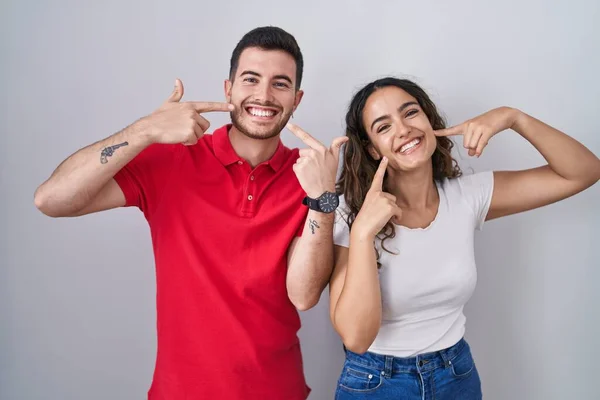 Young Hispanic Couple Standing Isolated Background Smiling Cheerful Showing Pointing — Zdjęcie stockowe