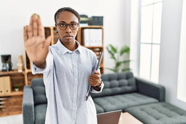 African woman working at psychology clinic doing stop sing with palm of the hand. warning expression with negative and serious gesture on the face.