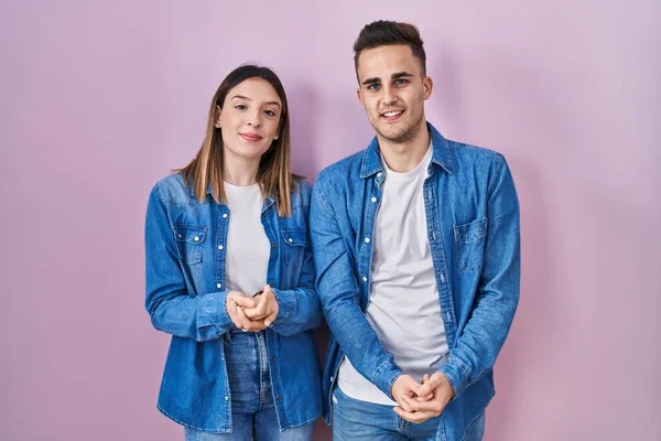 Unga Latinamerikanska Par Står Över Rosa Bakgrund Med Händerna Tillsammans — Stockfoto