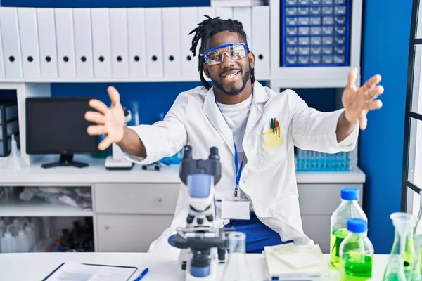 科学研究所で働いているアフリカ人の男性は 抱擁のために開いた腕で笑顔カメラを見ています 幸せを受け入れる陽気な表情 — ストック写真