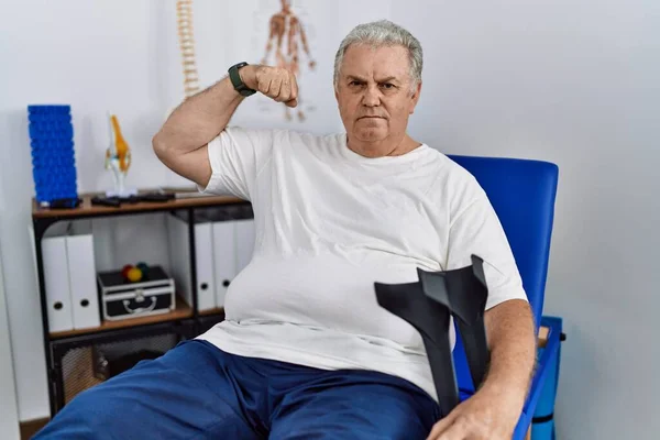 Senior Caucasian Man Physiotherapy Clinic Holding Crutches Strong Person Showing — Stock Photo, Image