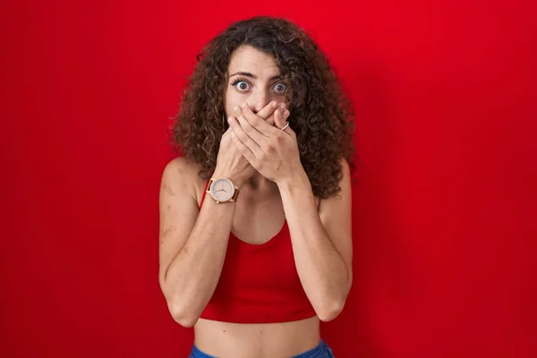 Hispanic Woman Curly Hair Standing Red Background Shocked Covering Mouth — Foto de Stock