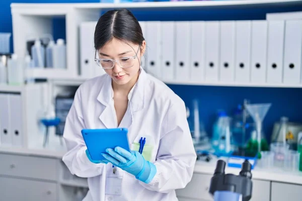Chinese woman scientist using touchpad working at laboratory