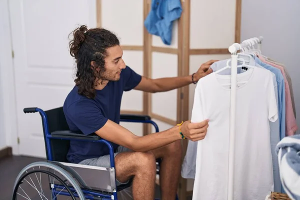 Young Hispanic Man Holding Clothes Sitting Wheelchair Bedroom — Stock fotografie